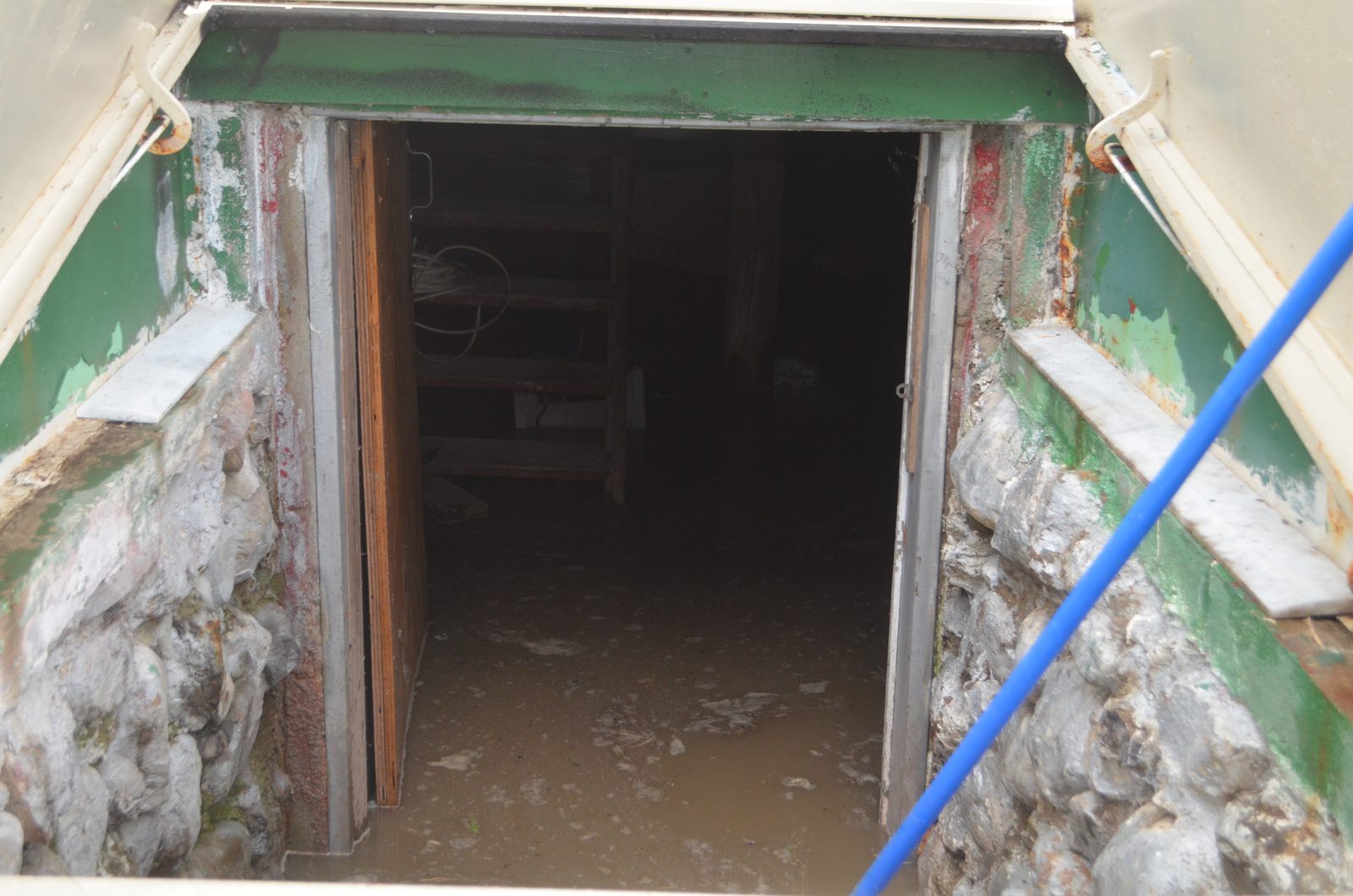 Looking down a cellar door into a basement with brown floodwater over the floor