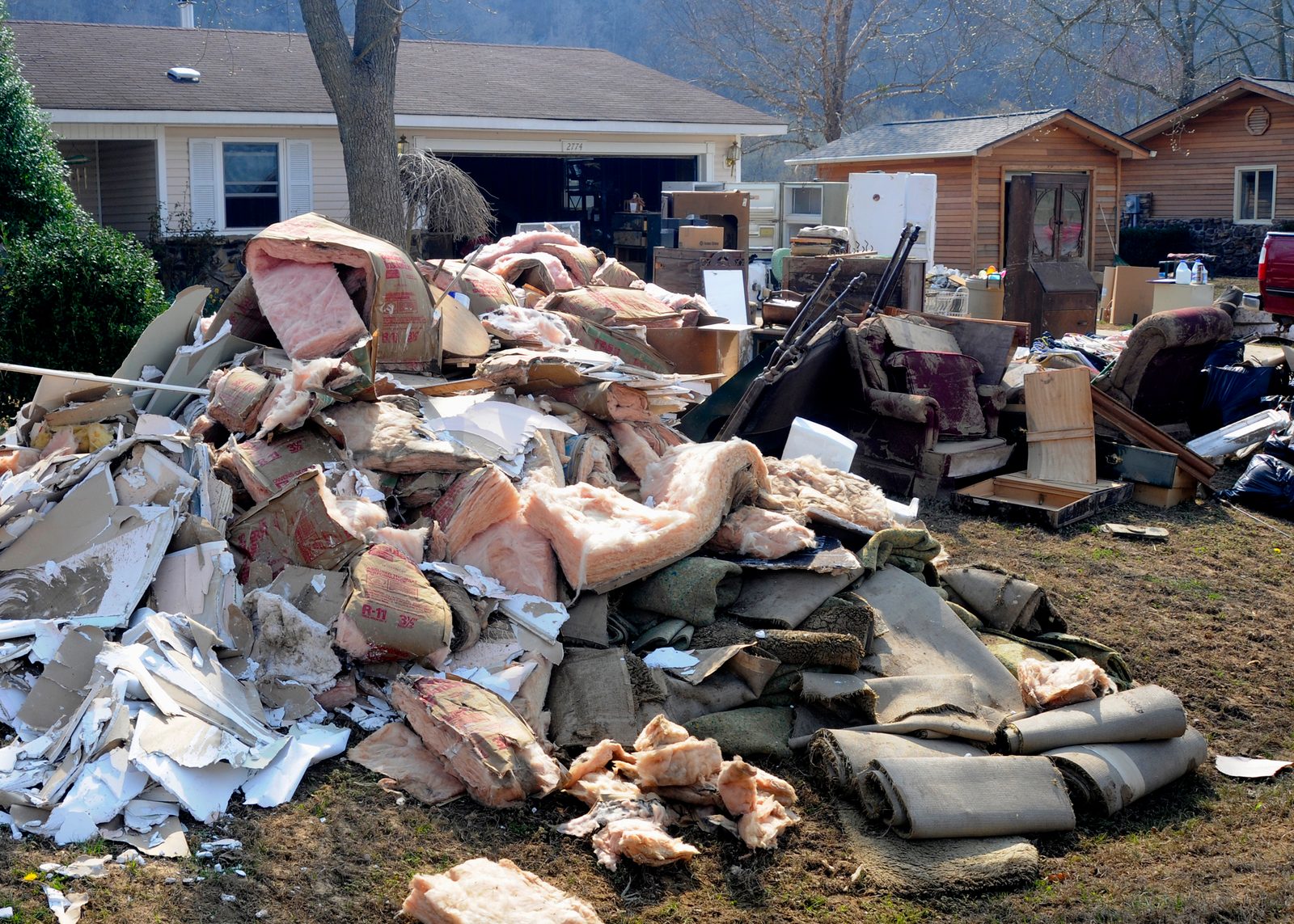 Wet insulation, drywall and carpet piled on a front lawn after a flood